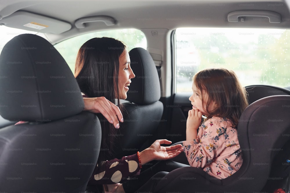 Mère avec sa fille à l’intérieur d’une voiture moderne ensemble.