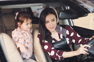 Mother with her daughter inside of modern automobile together.