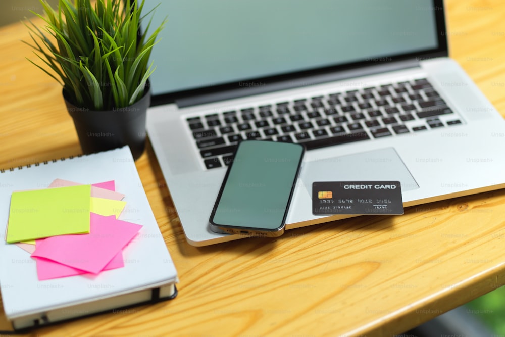 Close up do telefone celular e laptop tela vazia maquete com cartão de crédito, notas adesivas na mesa