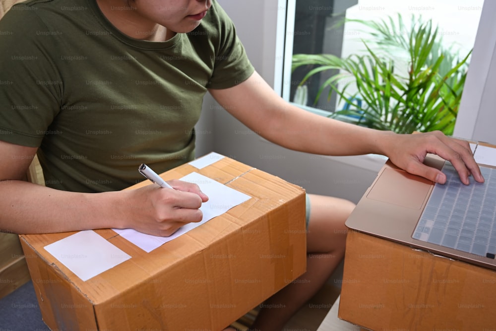 Small business owner writing address on cardboard box. Online selling.