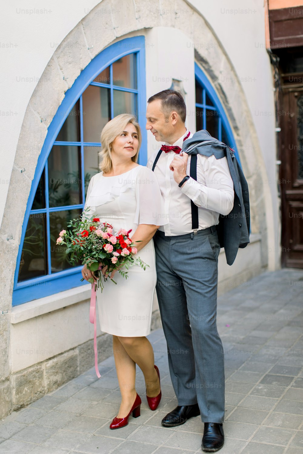 Lächelndes glückliches, verliebtes reifes Ehepaar bei einem Date in der Altstadt, das dicht beieinander auf einem ruhigen Spaziergang steht und sich gegenseitig ansieht