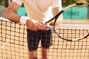 Nahaufnahme des älteren Mannes in weißem Hemd und schwarzen sportlichen Shorts, der auf dem Tennisplatz ist.