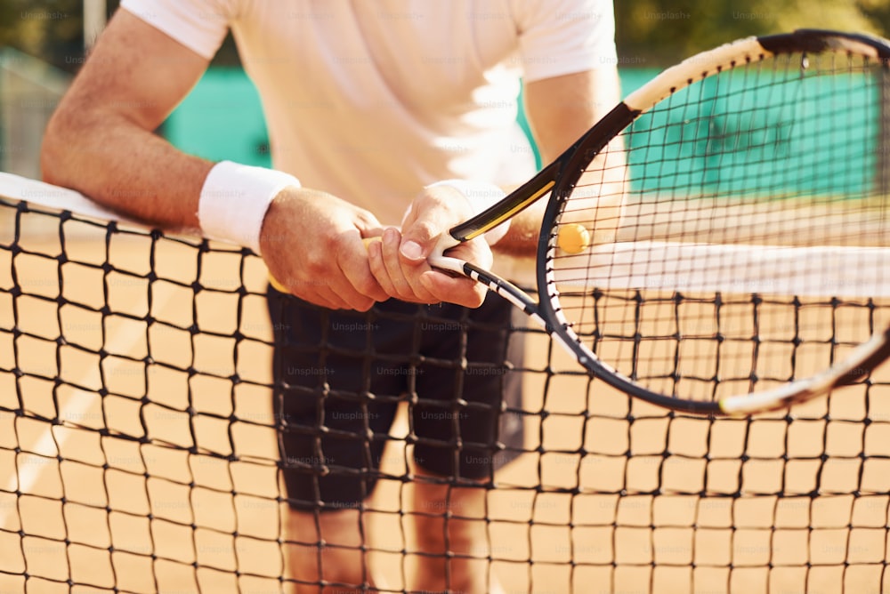 Close up view of senior man in white shirt and black sportive shorts that is on tennis court.