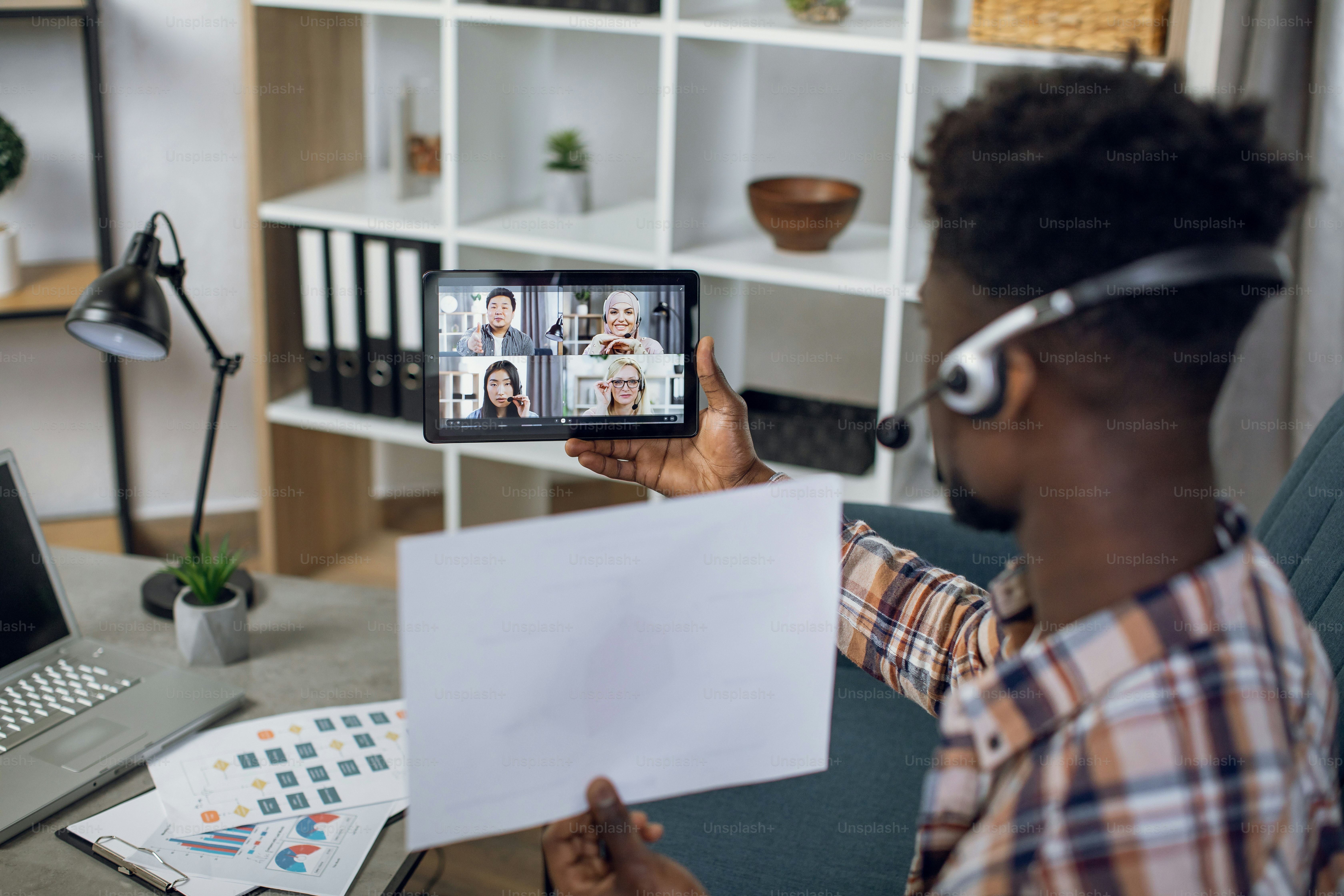 Back view of black man using digital tablet for video call with ...