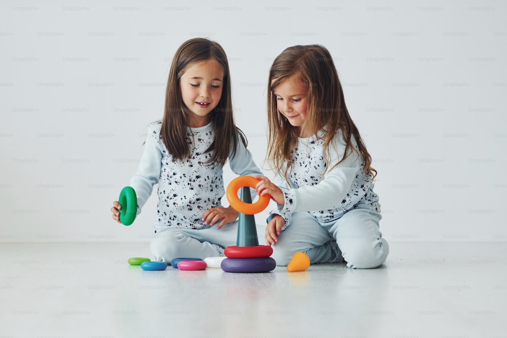 Playing with toy. Two cute little girls indoors at home together. Children having fun.