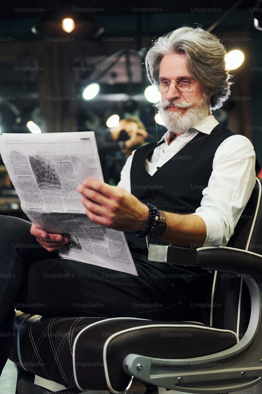 신문 읽기. 회색 머리와 수염을 가진 세련된 현대 노인이 실내에 있습니다.