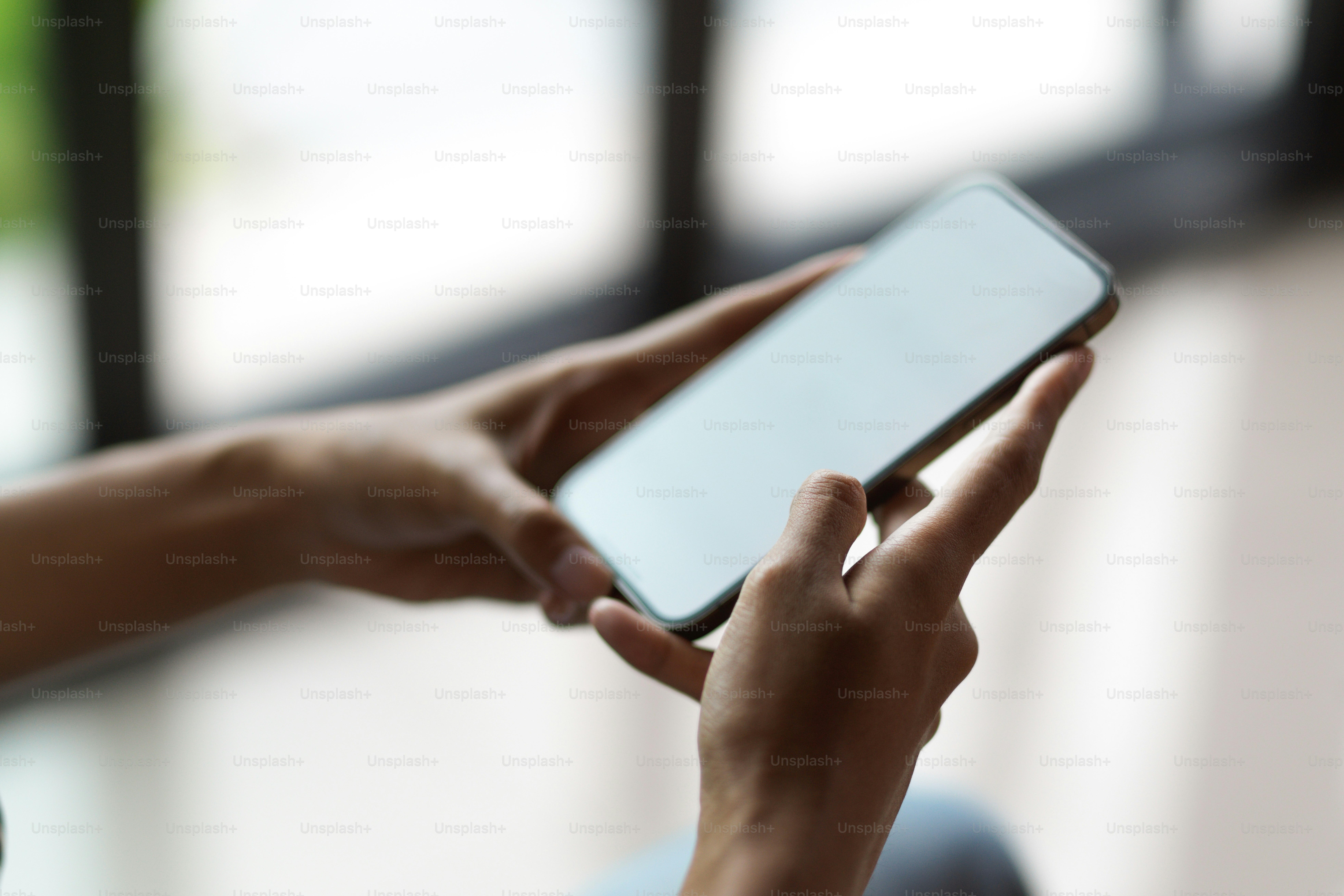 ぼやけた背景でスマートフォンを介してインターネットを閲覧している女性の手の接写