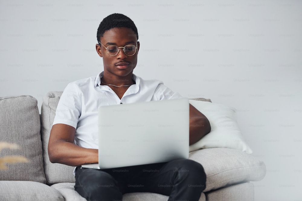 Young african american man in formal clothes indoors with laptop in hands.