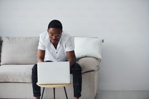 Young african american man in formal clothes indoors with laptop in hands.