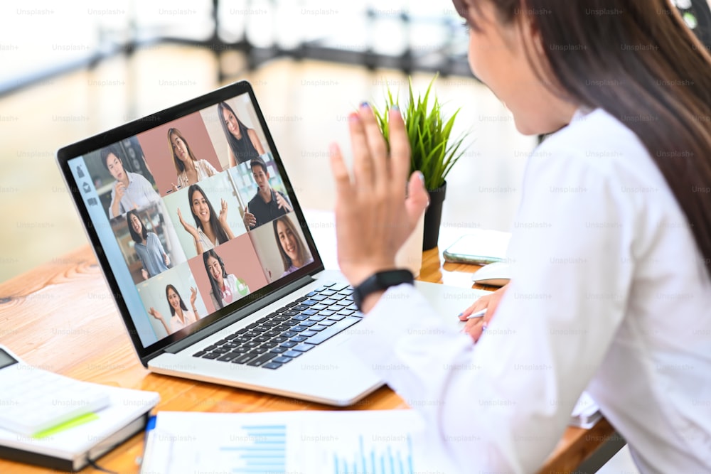 Female employee talking on video call with diverse colleagues on laptop computer.