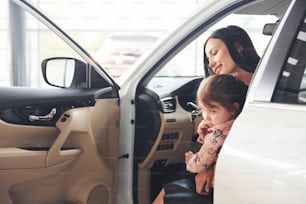 Mother with her daughter inside of modern automobile together.