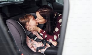 Mother with her daughter inside of modern automobile together.