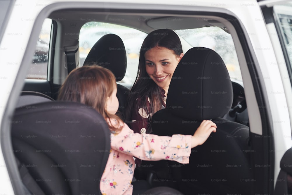 Mãe com sua filha dentro do automóvel moderno juntos.