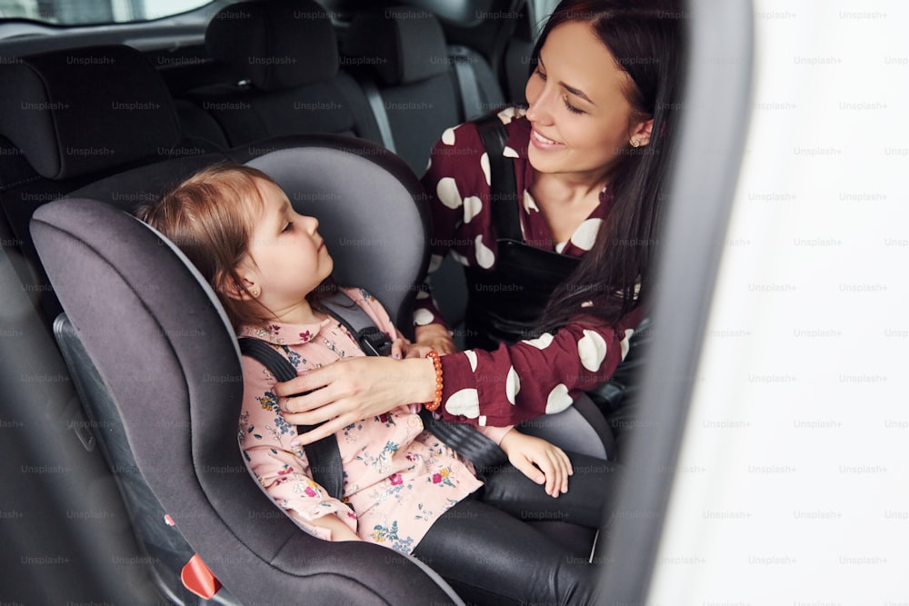 Mãe com sua filha dentro do automóvel moderno juntos.