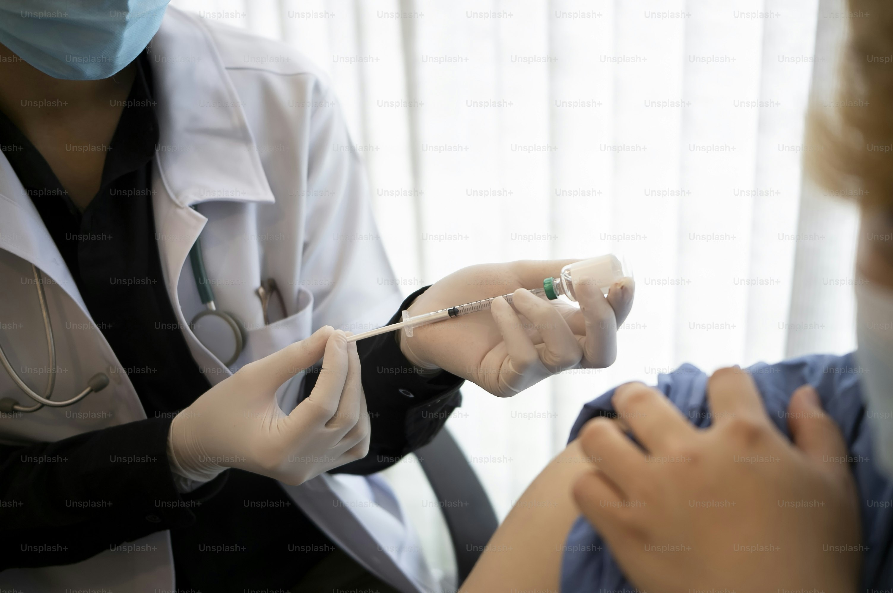 Doctor giving injection of vaccine to male patient.