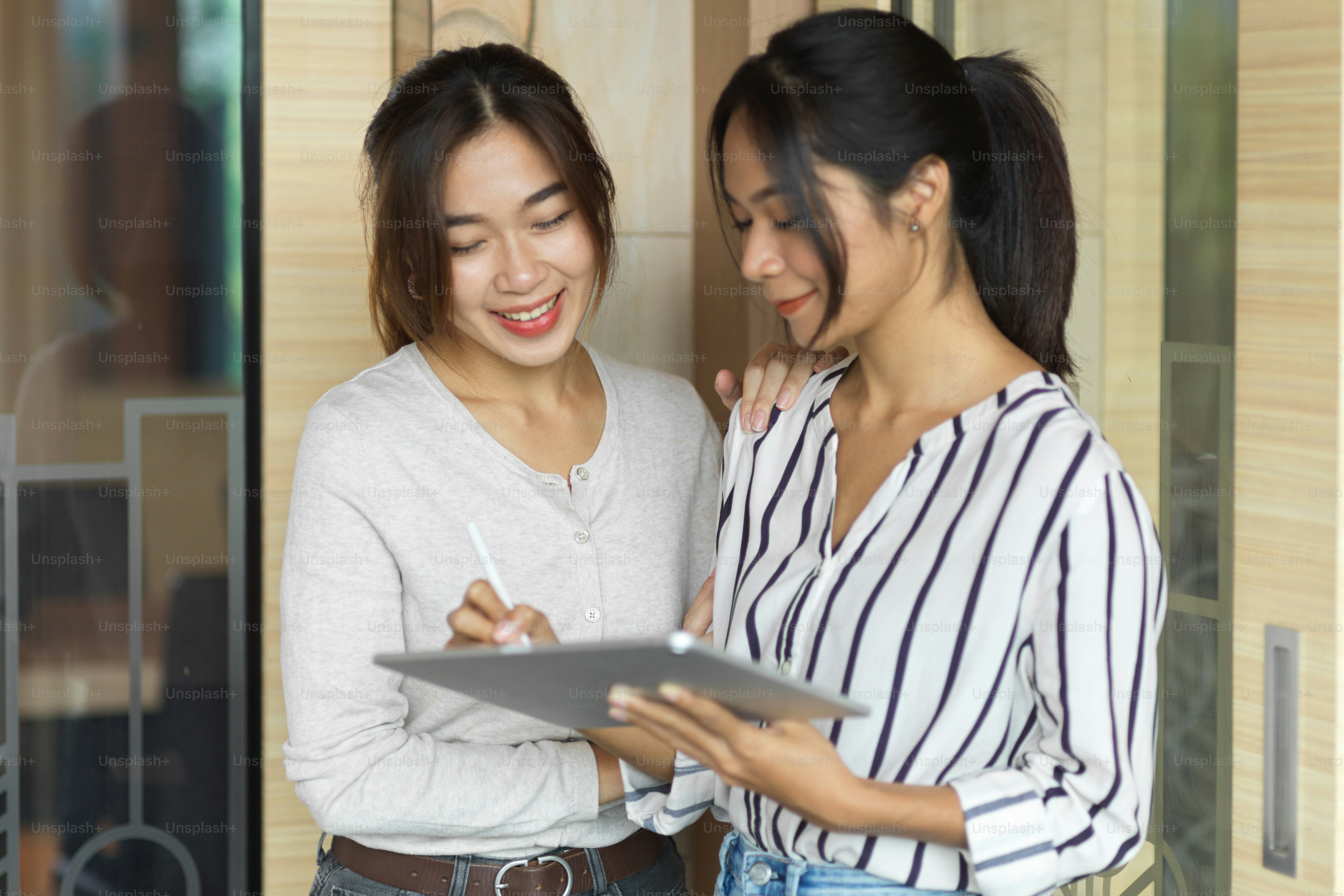 Portrait de 2 femmes d’affaires discutant et regardant sur tablette ...