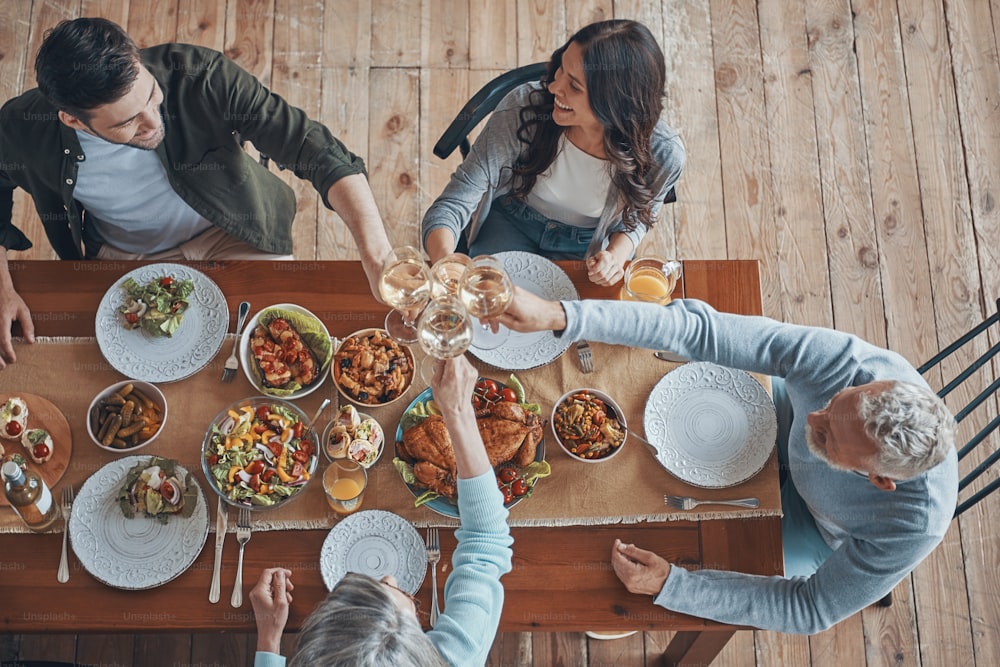 Top view of multi-generation family toasting while having dinner together