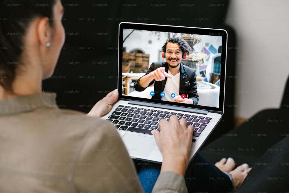 Back view of business latin woman talking to her mexican colleagues in video conference business team using laptop for a online meeting in video call working from home in Latin America