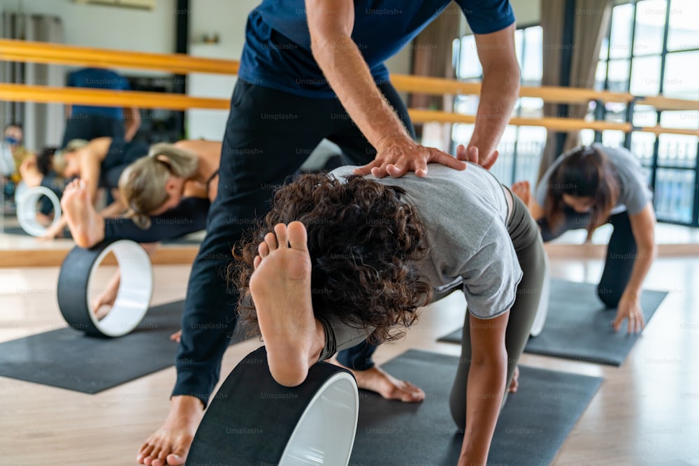 Gruppo di donna asiatica sana che utilizza attrezzature da yoga per praticare l'allenamento di yoga e la lezione di esercizi di fitness per lo stretching del corpo insieme all'istruttore nello studio di yoga. Le amiche del benessere si godono l'attività al chiuso, lo stile di vita sportivo