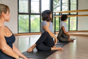 Gruppe gesunder asiatischer Frauen in Yogakleidung, die gemeinsam Yoga-Training und Körperdehnungs-Fitnessübung im Yoga-Fitnessstudio praktizieren. Attraktive Freundinnen genießen Indoor-Activity-Sport-Lifestyle