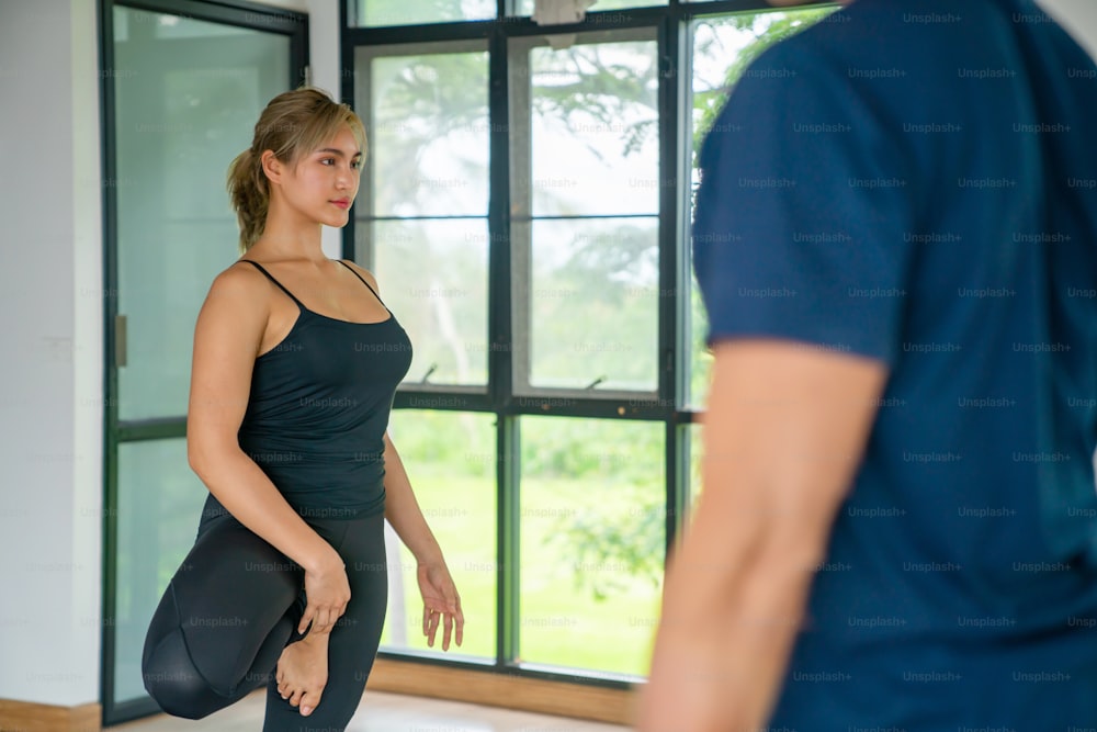 Un groupe de femmes asiatiques en bonne santé pratique le yoga et les cours d’exercices de remise en forme d’étirement du corps avec un instructeur masculin dans un studio de yoga. Les amies apprécient l’activité à l’intérieur, le style de vie et l’entraînement sportif.