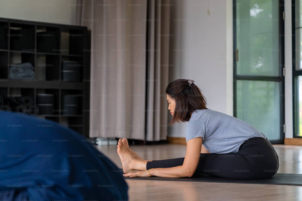 Il gruppo di donne asiatiche sane fa pratica di yoga e lezione di esercizi di fitness per lo stretching del corpo insieme all'istruttore maschio nello studio di yoga. Le amiche amano l'attività al chiuso, lo stile di vita e l'allenamento sportivo.