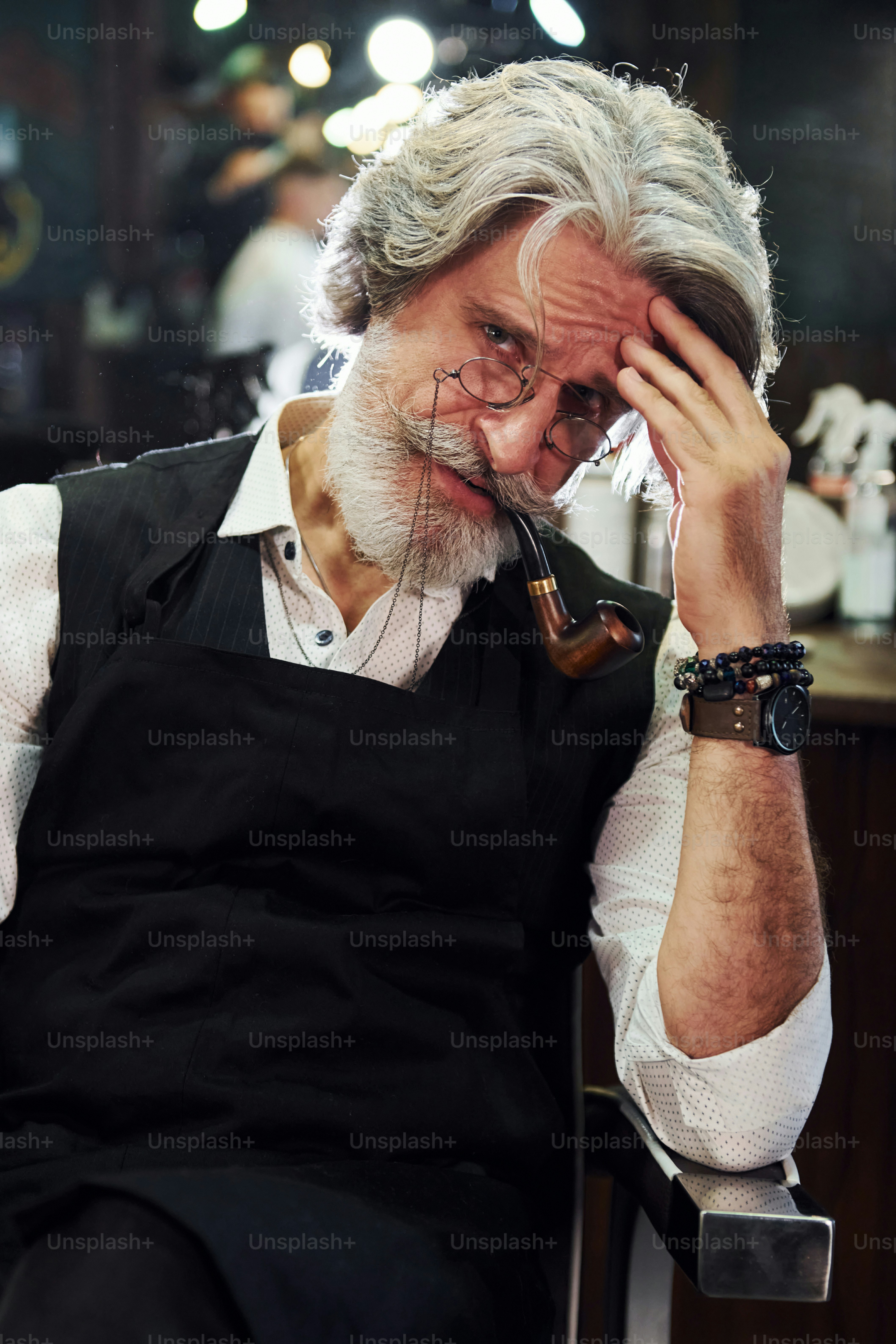 En barbería. Elegante hombre mayor moderno con cabello gris y barba está en el interior