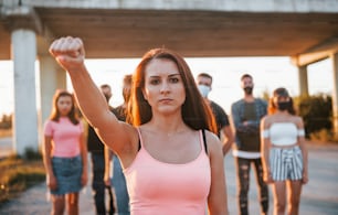 Woman on the front of crowd. Group of protesting young people that standing together. Activist for human rights or against government.