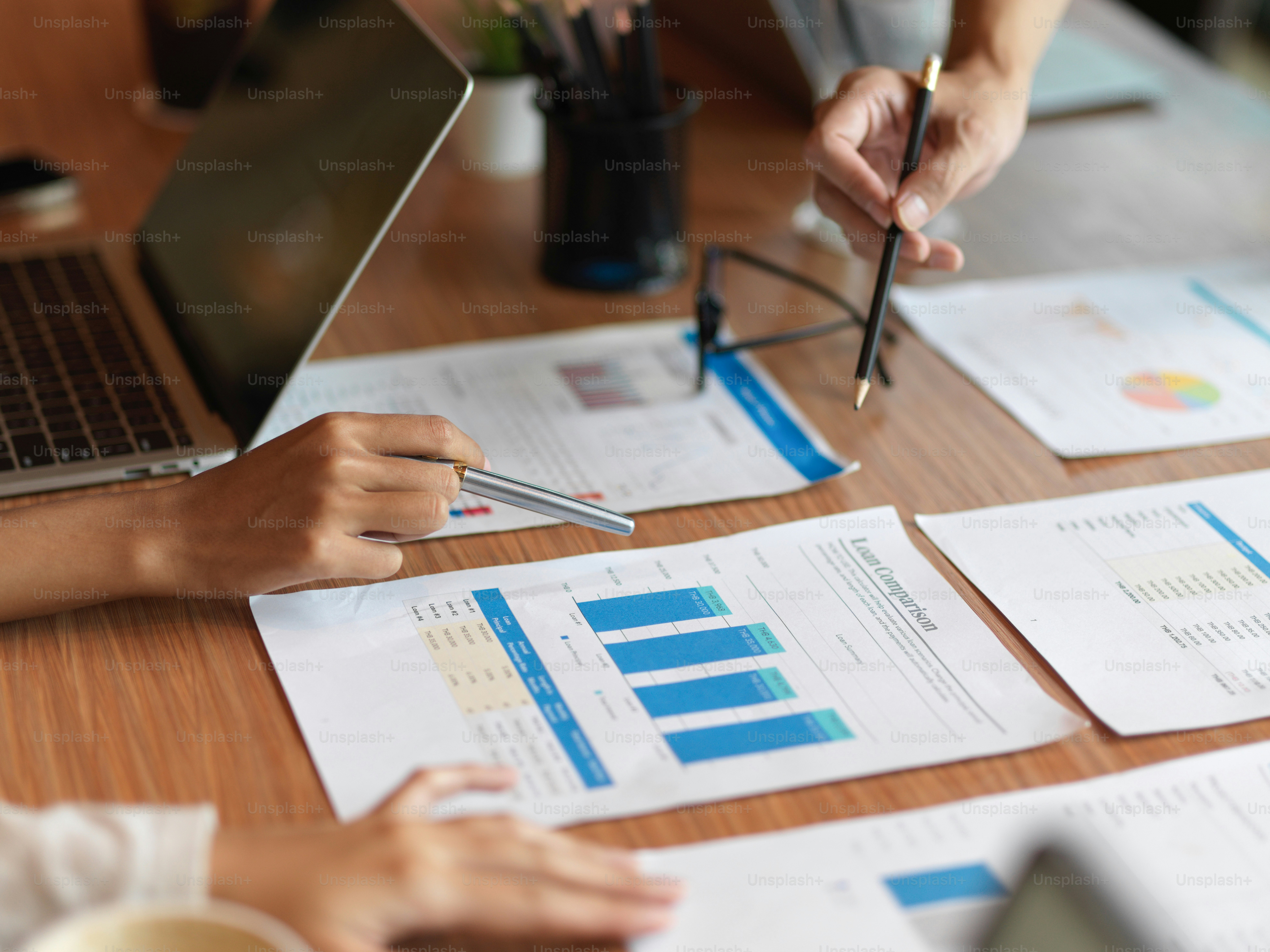 Close up of financial team consulting about loan comparison for company in the meeting room with loan comparison report, laptop and office supplies