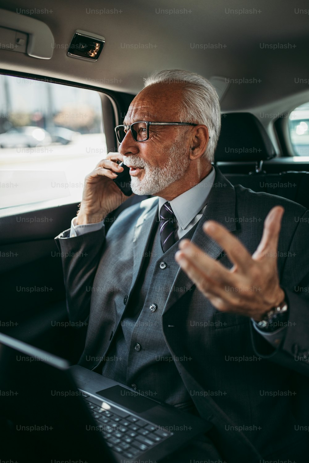 고급 자동차의 뒷좌석에 앉아있는 잘 생긴 고위 사업가. 그는 노트북을 사용하고 감정적으로 반응합니다. 기업 비즈니스 개념의 교통.