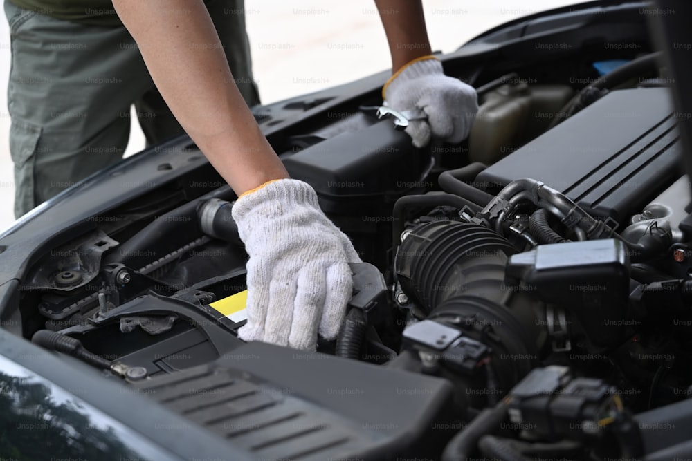 Cropped shot mechanics working on car engine in mechanics garage.