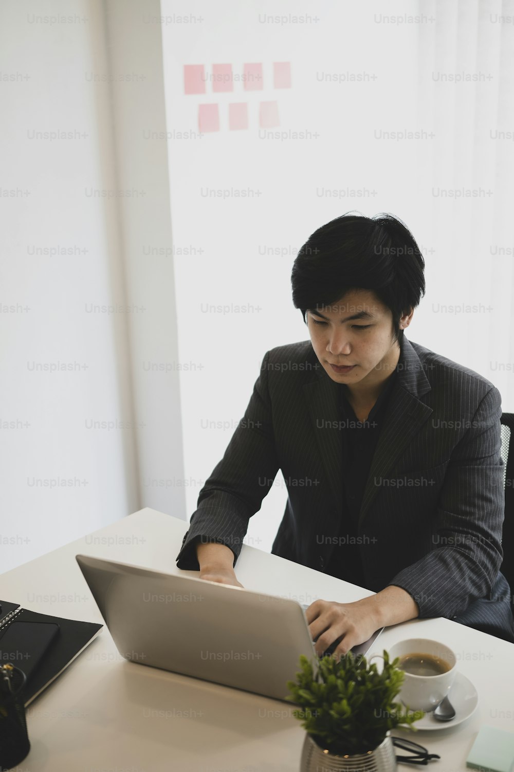 Handsome businessman siting in modern office and working with laptop computer.