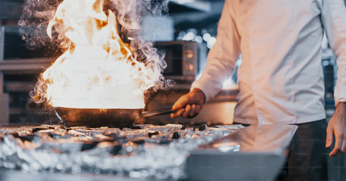 Working Condition Cook Frying pan is on fire. Chef in white uniform cooking food at kitchen ...