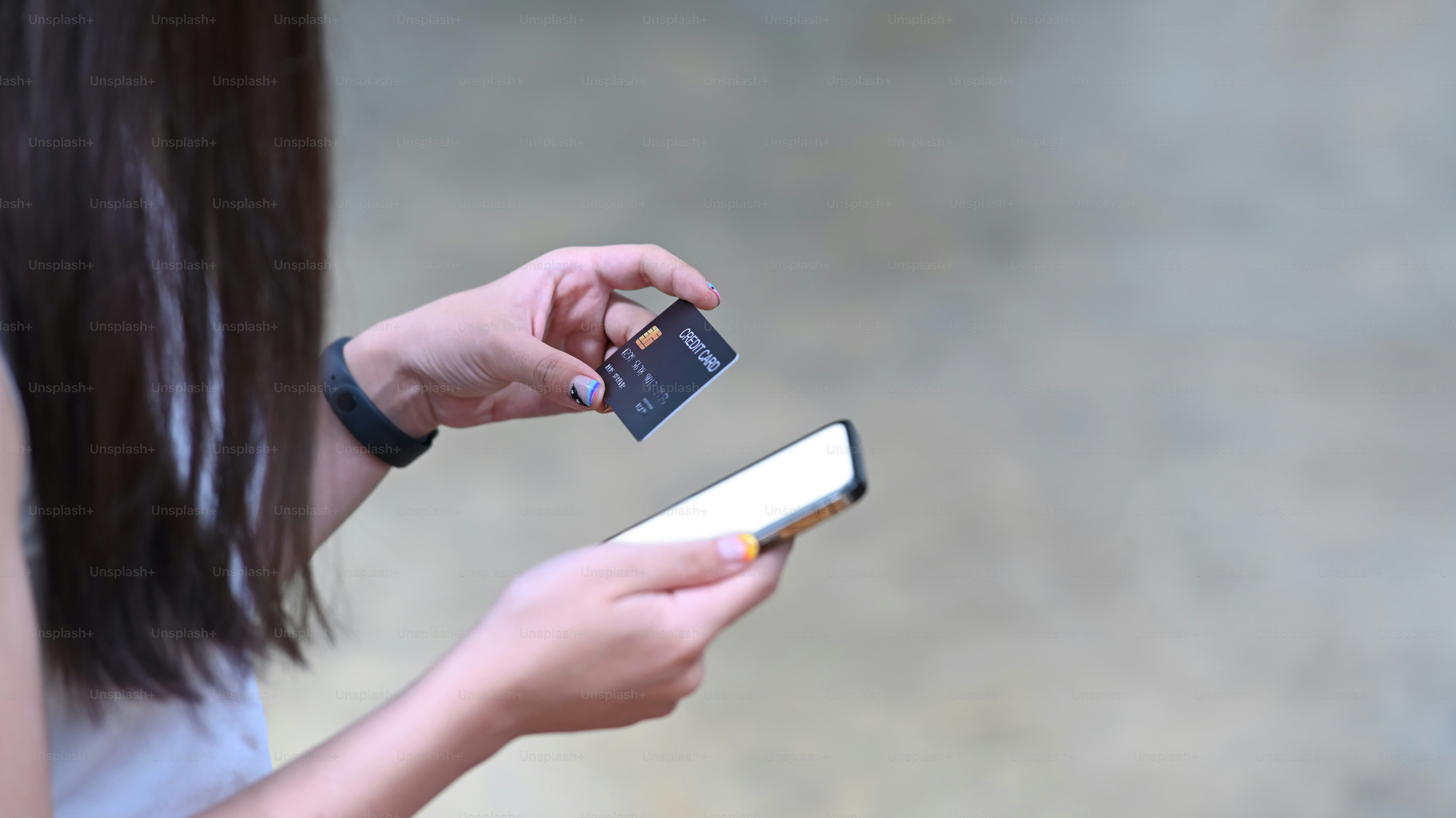 Woman hands holding credit card and using smart phone for banking online or online shopping.