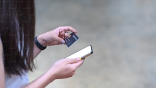Woman hands holding credit card and using smart phone for banking online or online shopping.