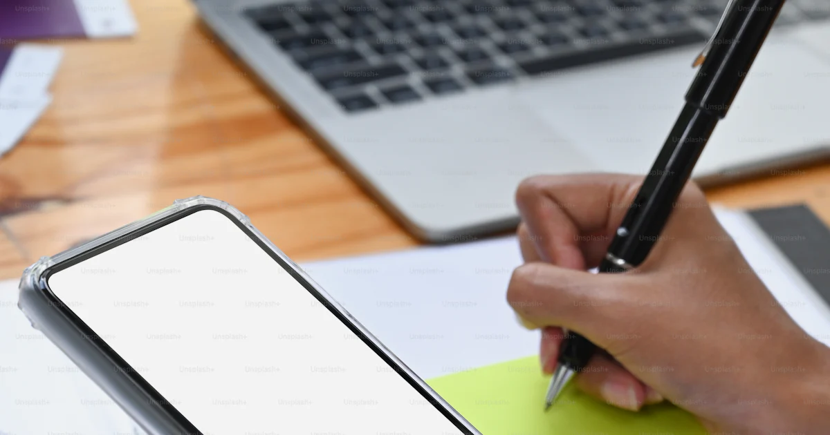 Businesswoman making note on sticky note and using smart phone. photo ...