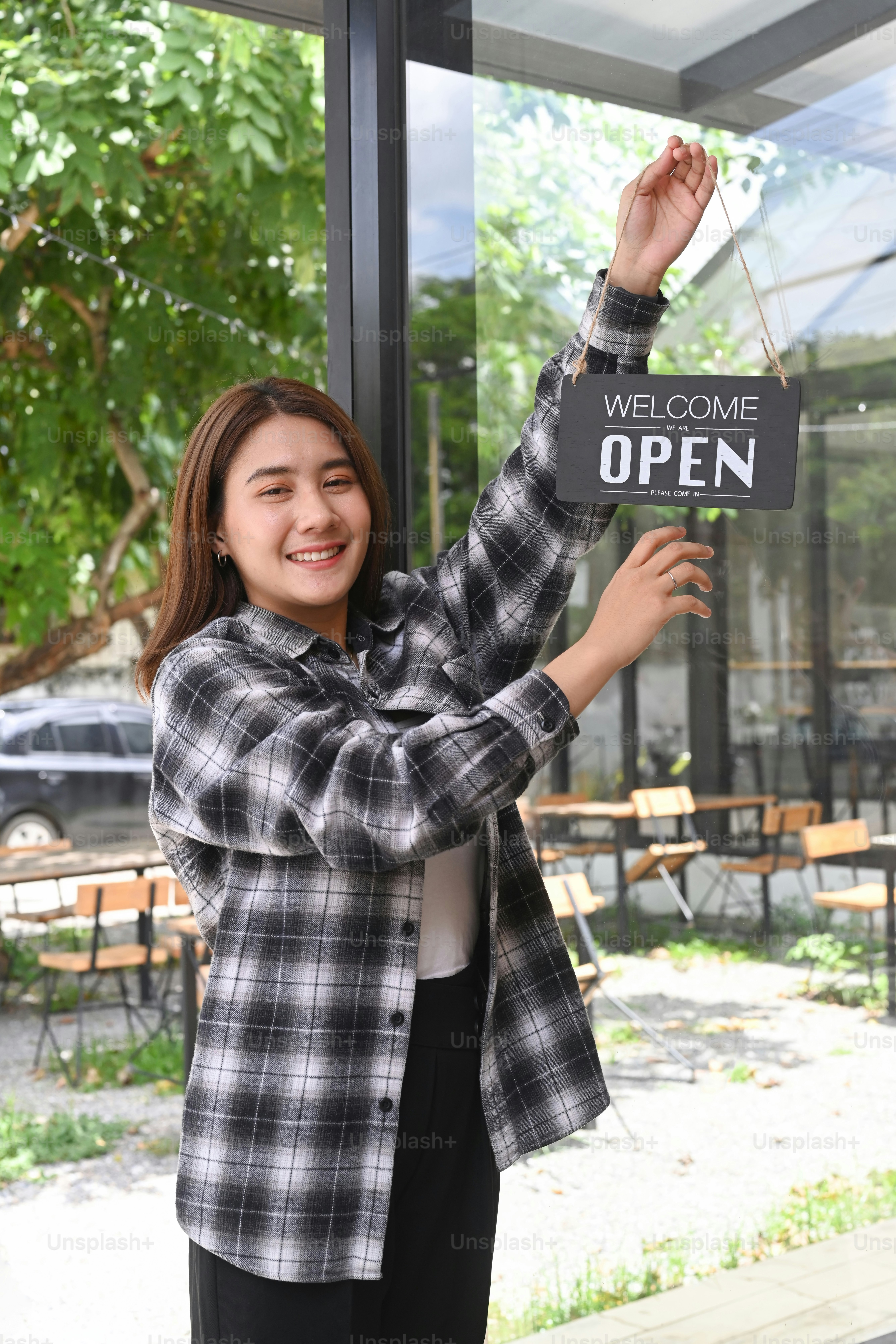 Friendly waitress woman hanging Open sign on the door glass