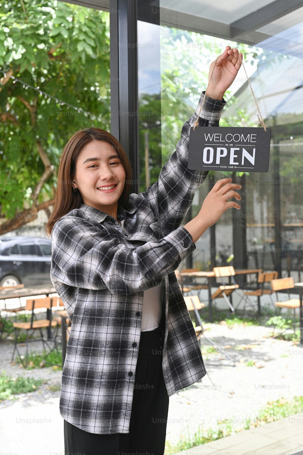 Friendly waitress woman hanging Open sign on the door glass.
