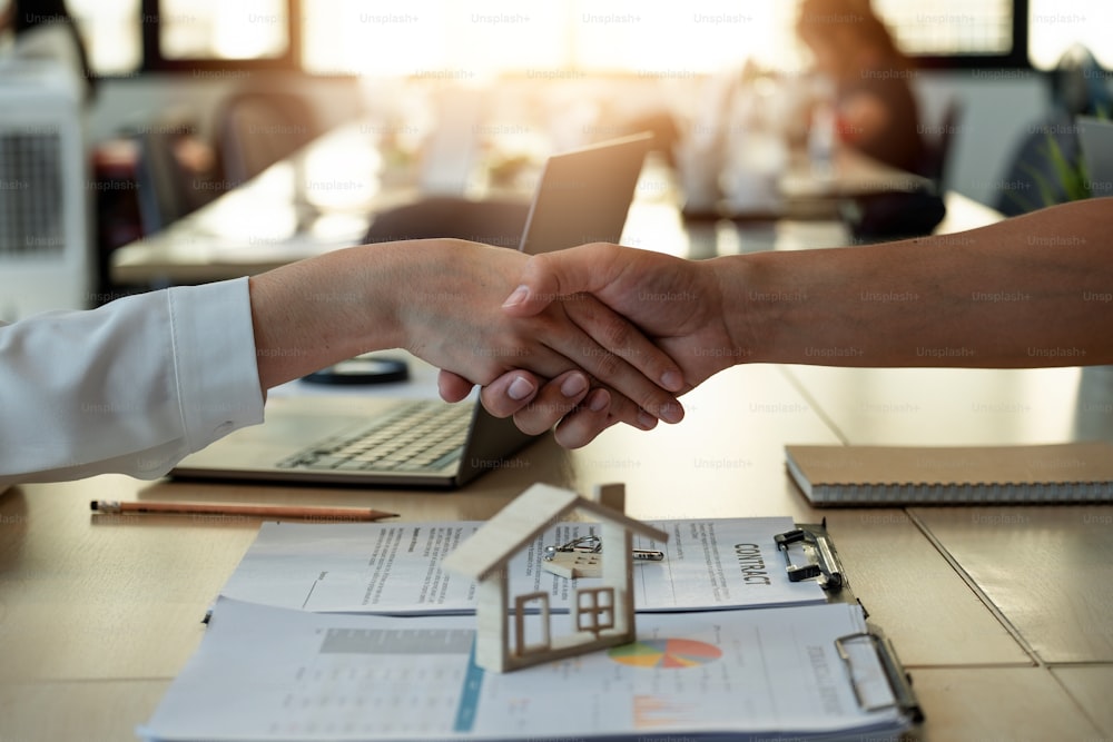 Handshake a successful real estate transaction in an office. Business people shake hands after signing a house purchase agreement