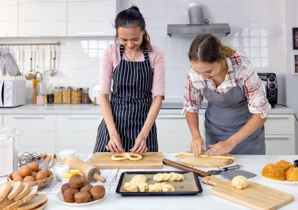 In kat's home, a smiling gorgeous woman and her friend are making breads together.