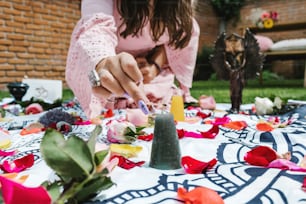 Latin woman lighting a black candle on rose petals for holistic therapy healing in Latin America