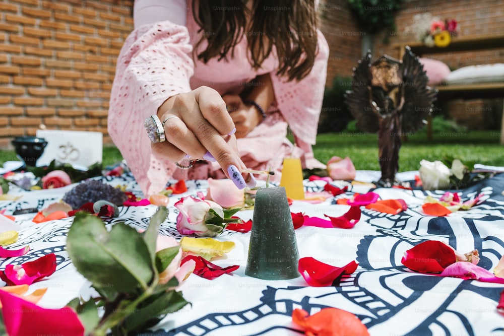 Latin woman lighting a black candle on rose petals for holistic therapy healing in Latin America