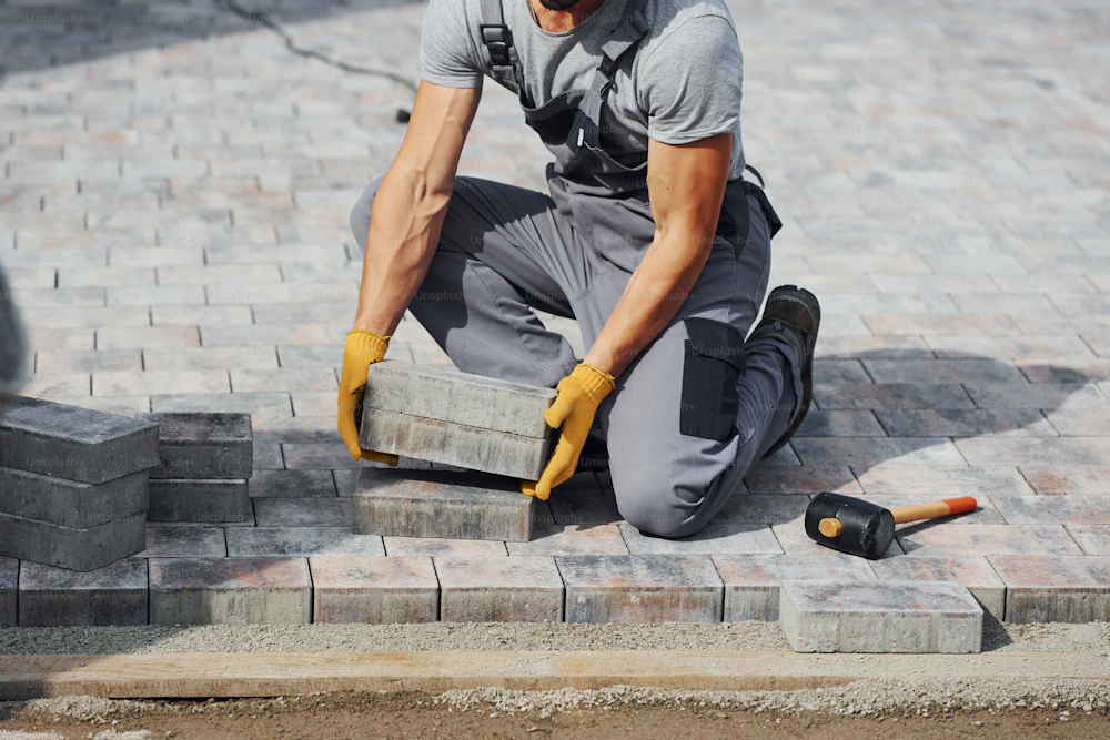 Construction worker laying paving bricks for a residential patio