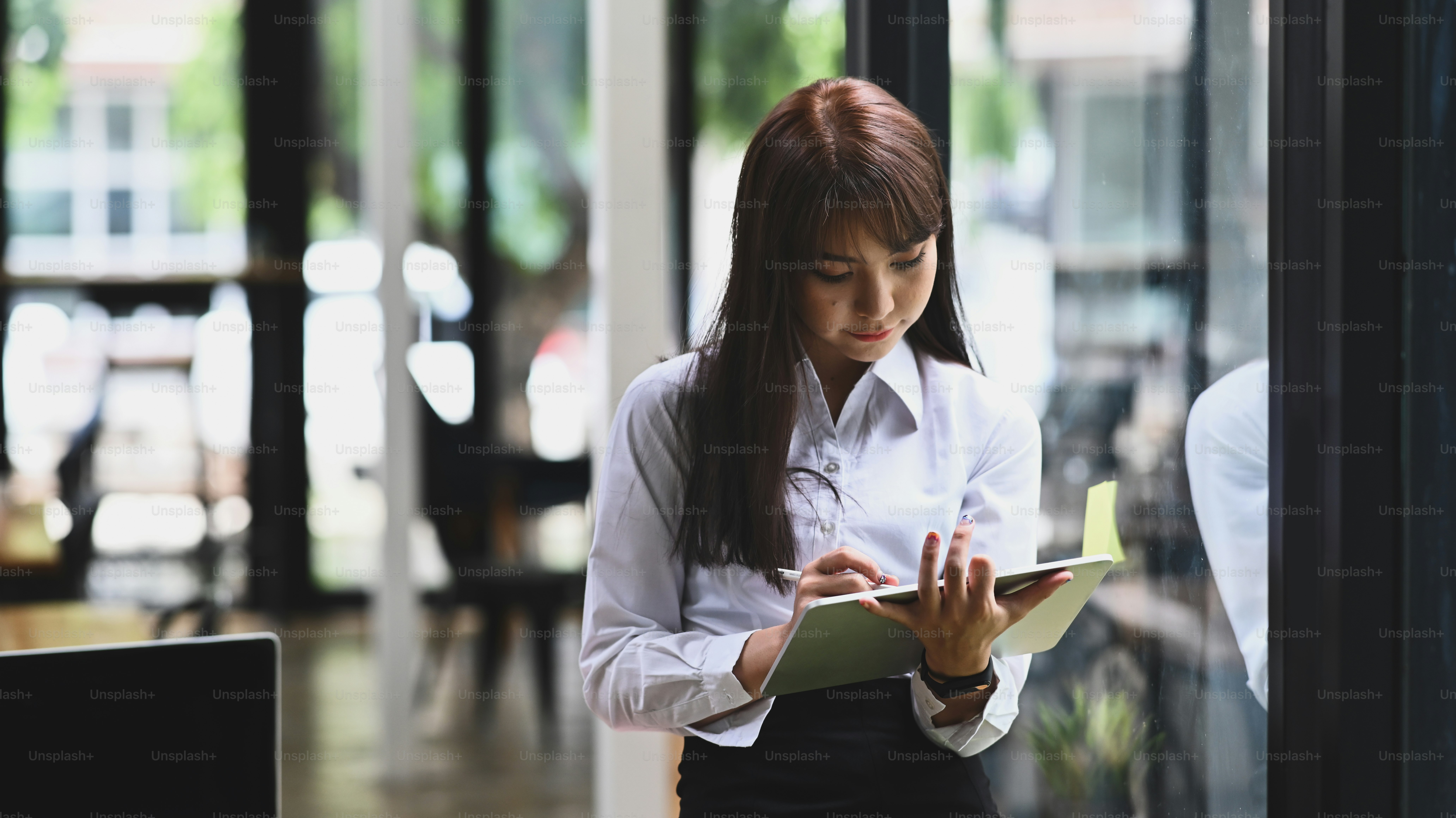 Beautiful businesswoman using digital tablet while standing in office.