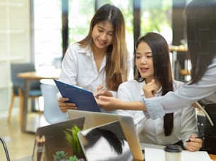 Business worker showing the data report to her colleague at office room, laptop, happy to work together, smiling, brainstorming