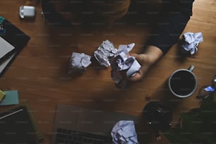 Above view stressed businessman crumpling paper at his table.