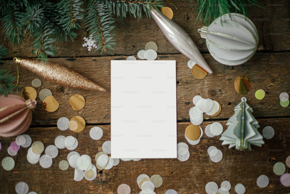 Christmas card mock up. Empty greeting card and christmas ornaments, decorations, confetti and pine branches on rustic wooden background. Flat lay. Space for text. Seasons greetings. Template