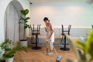 Junge asiatische Frau Café Barista Reinigung Café vor der Eröffnung. Kellnerin bereitet Bistro-Restaurant für den Service für Kunden vor. Kleinunternehmer und Teilzeitbeschäftigter Konzept