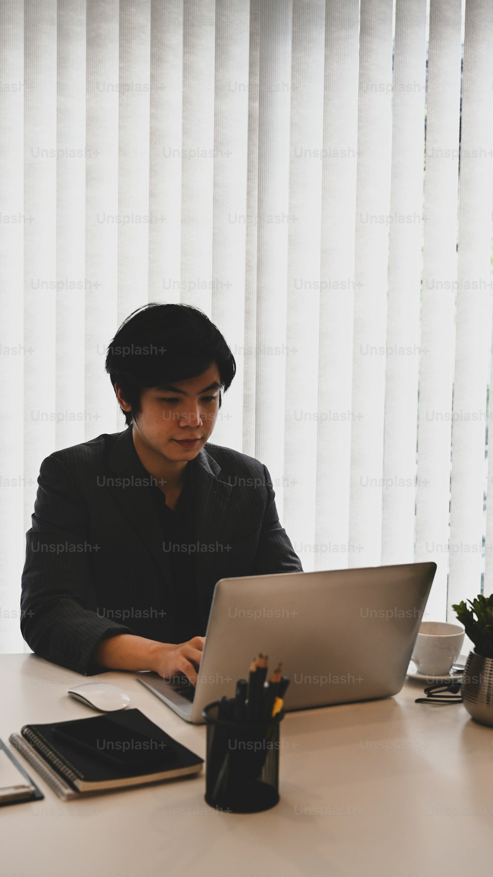 Successful businessman using computer laptop while sitting in modern office.