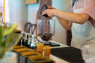 Un employé à temps partiel d’un café d’homme asiatique prépare du café chaud dans une machine à café. Barista masculin faisant un expresso à partir de café moulu dans une cafetière. Propriétaire d’une petite entreprise et concept de travail à temps partiel.
